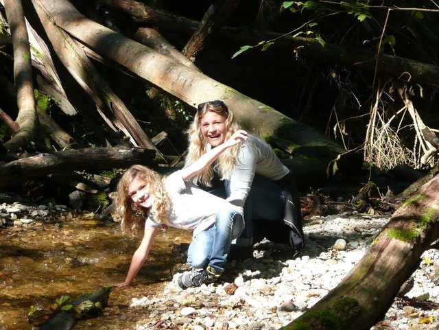 Mädchen mit Mutter im Wald am Bach