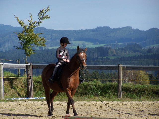 Kind lernt auf eigenem Reitplatz reiten