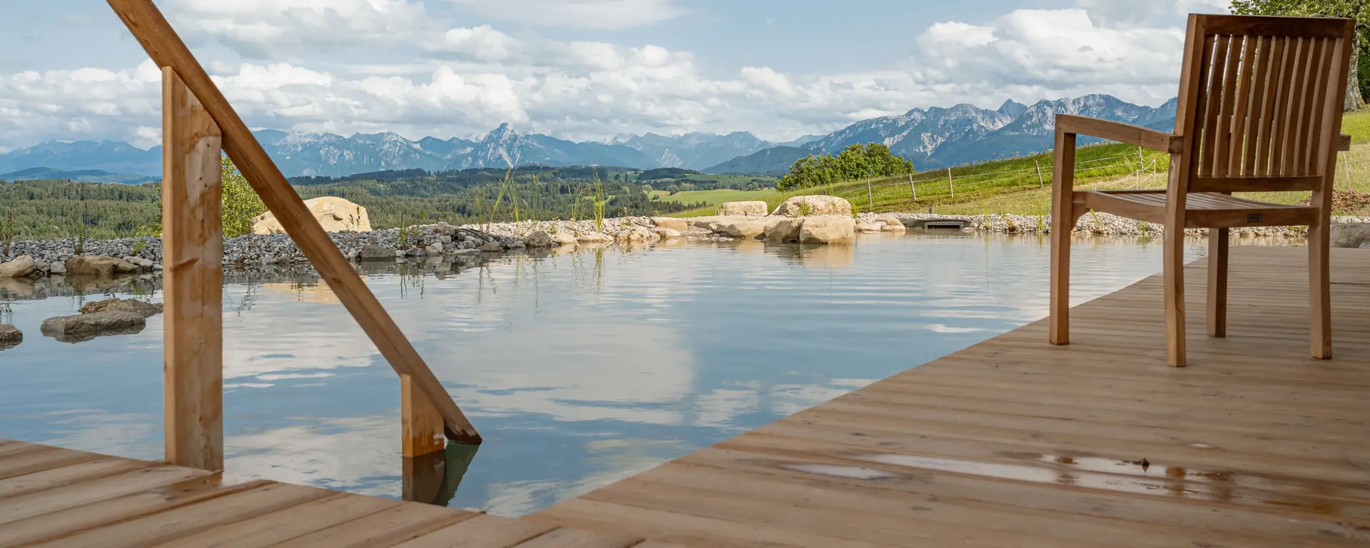 Blick ins Allgäu vom hofeigenen Schwimmteich - © Ferienhof Tronsberg, Fotografin Melanie Fielenbach Im Teich schwimmen und in die Allgäuer Bergwelt blicken.