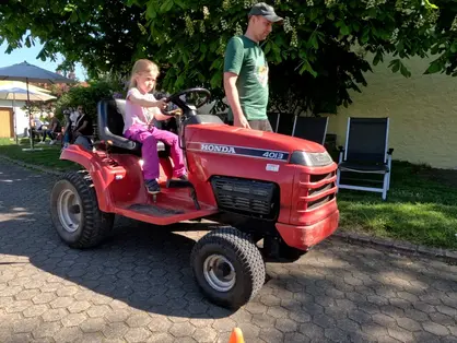 Kinder Tretfahrzeuge © Andreas Kern Mädchen auf roten Trettraktor