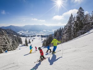 Familie auf sonniger Skipiste am Brauneck bei Lenggries im Tölzer Land