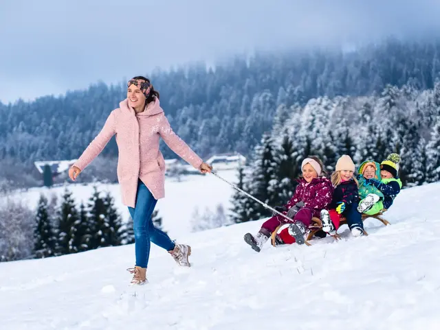 Mama mit Kinder am Schlittenfahren