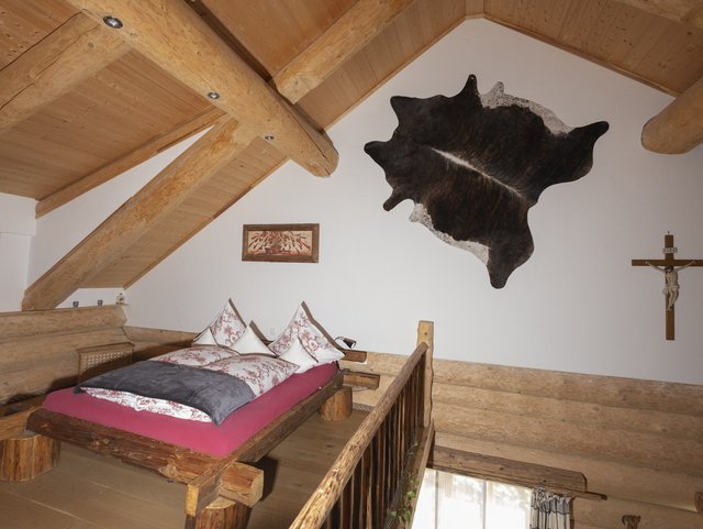 Bett in der offenen Galerie am Holzhaus Lugerhof