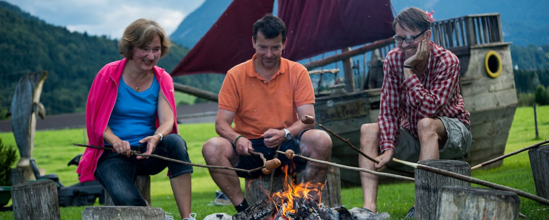 Erwachsene sitzen gemütlich am Lagerfeuer in einer Runde