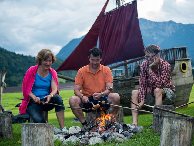 Erwachsene sitzen gemütlich am Lagerfeuer in einer Runde