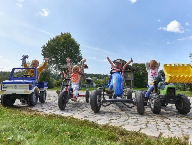 Auf Tretfahrzeugen durch den Hof auf dem Kinderbauernhof